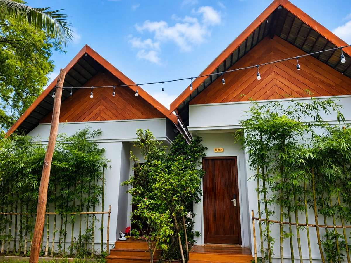 A twin-gabled garden bungalow framed by bamboo